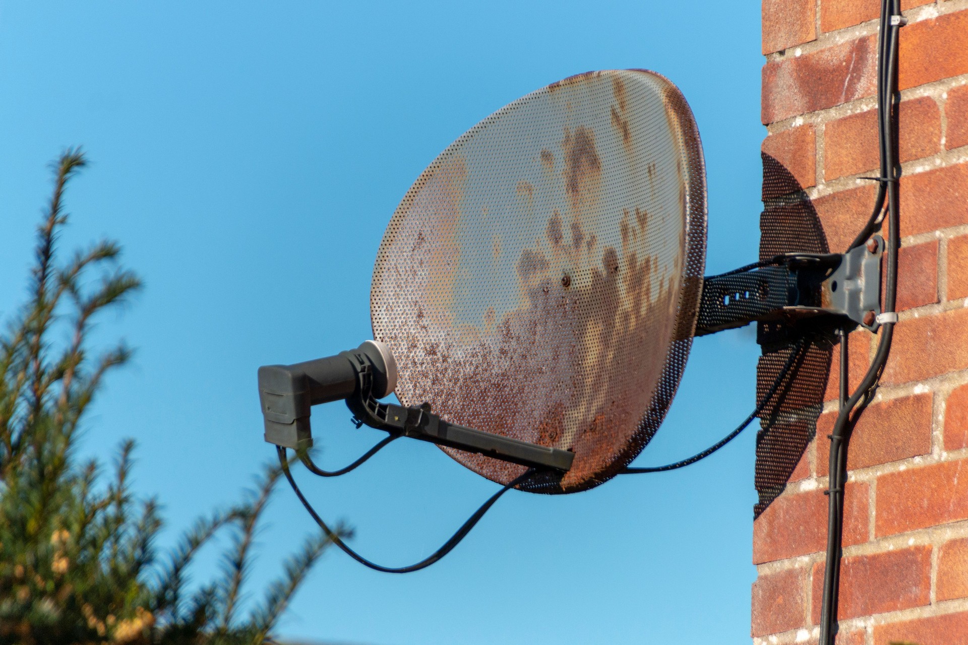 a close up view of a old rusted satellite dish attached to a brick wall