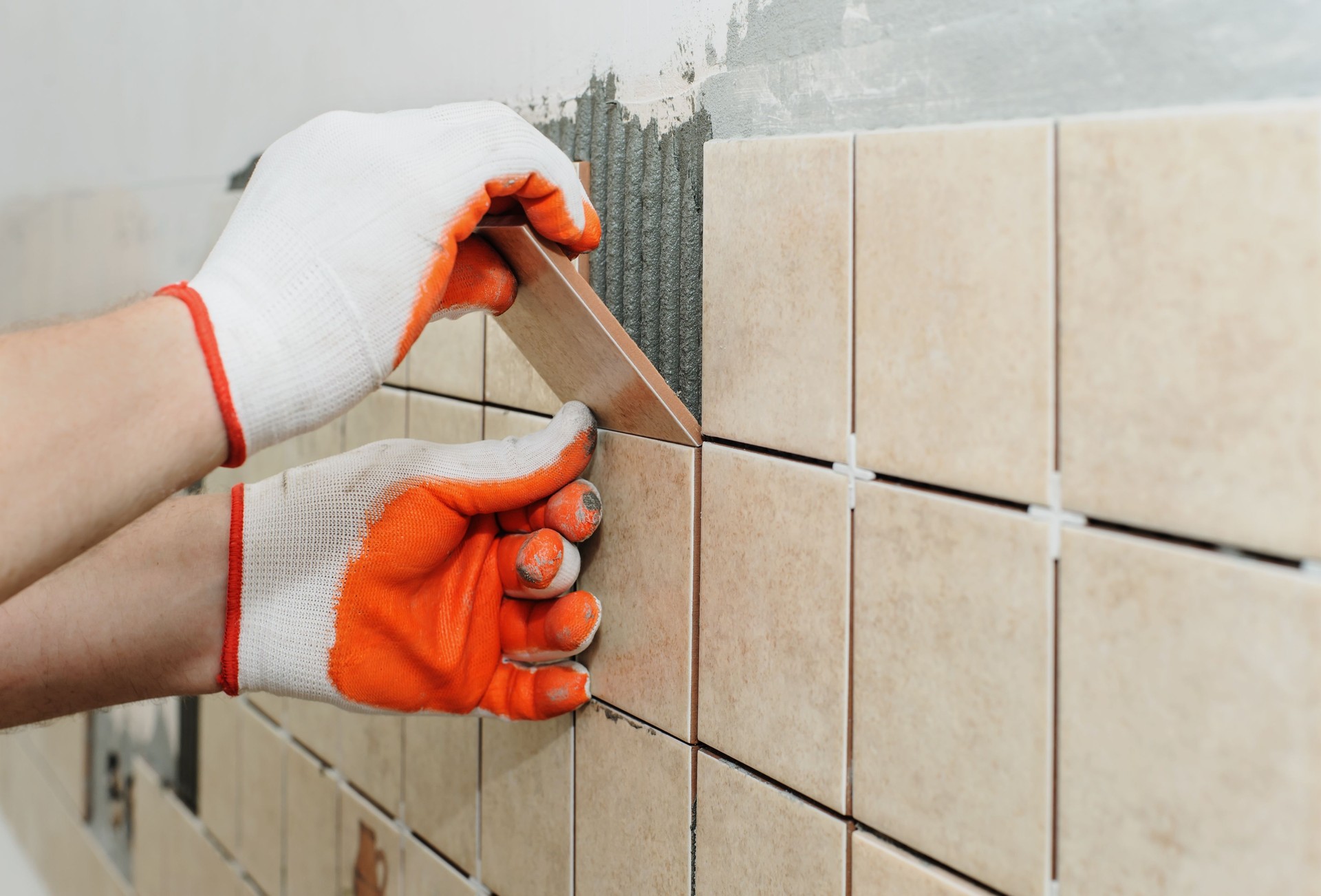 Worker  putting  tiles on the wall in the kitchen.